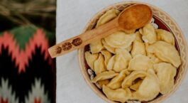 Schale mit goldgelben Klößen und Holzlöffel auf gedecktem Tisch